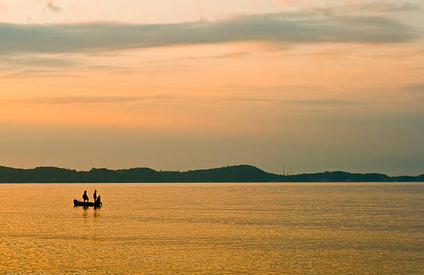 Men in a boat at dawn stock photo