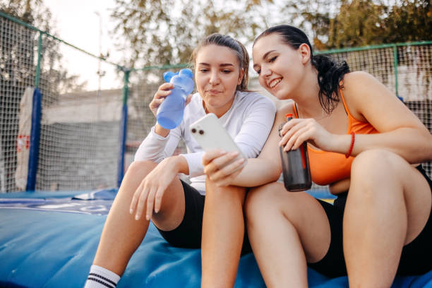 istock Two young and fit woman looking at mobile phone after training on trampoline 1722329780