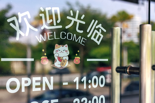 A Chinese character 'open' sign on a retail store hangs on the door at the entrance.