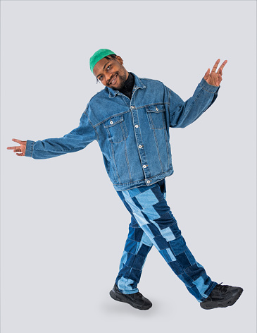 Full length portrait of a fashionable young african man in denim wear posing over white background