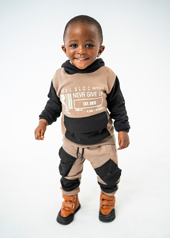 Full length portrait of innocent small boy standing over white background and smiling