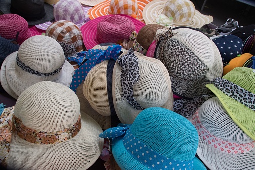 A selection of vibrant patterned hats with decorative bows arranged in a line on display