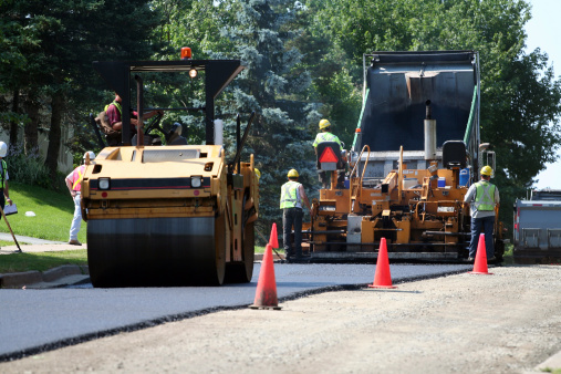An asphalt spreader is used to place the first layer of asphalt on a city street renewal project.