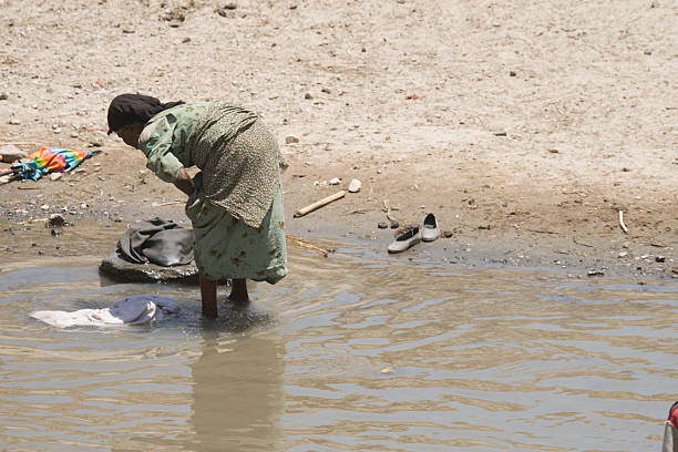 young woman washing her family's clothes along the muddy banks and  in the dirty water of the Usumacinta River, in the El Peten area of the rainforest in Guatemala