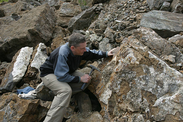 Geologist scientist man looking at rock in quarry geologist scientist looking at rock outcrop with his hammer geologist stock pictures, royalty-free photos & images