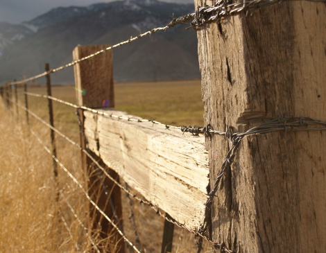 Old wooden fence with barbed wire in the wild west.