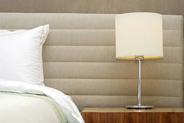 luxury hotel room setting with bed, pillows, bedside table and lamp