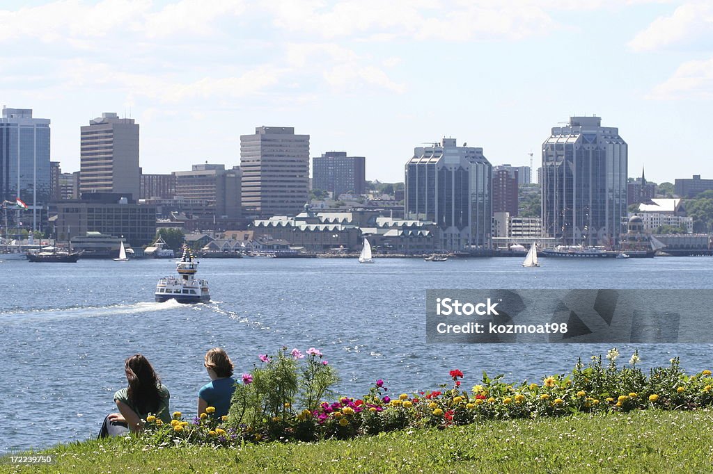 Halifax Harbor On A Summer Day Two people relax and enjoy a scenic view of Halifax City and harbor from the shores of Dartmouth on a hot summer day. Halifax Regional Municipality - Nova Scotia Stock Photo