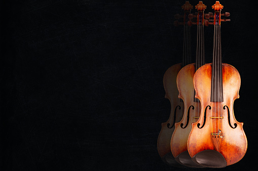 Three violins on black background with scratches - Copy space
