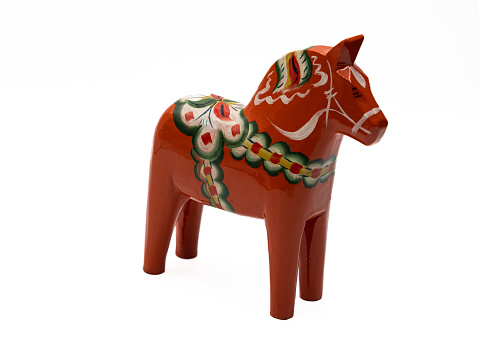 Traditional Swedish hand made craft, a Dala Horse (Dalahäst) carved in wood and colorfully painted, isolated on white background.