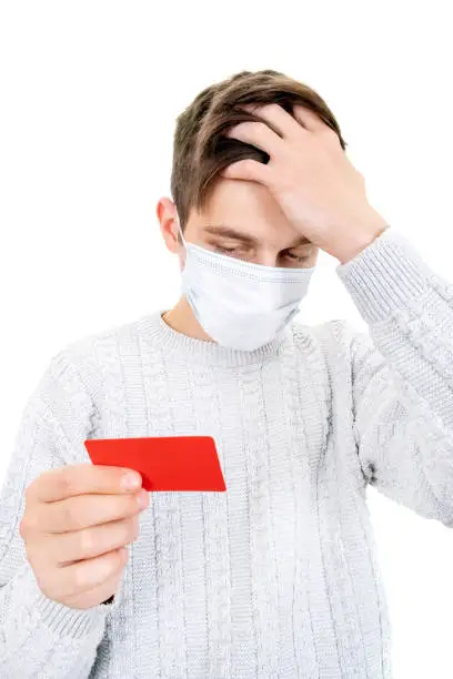Unhappy Young Man in Flu Mask hold a Bank Card Isolated on the White Background