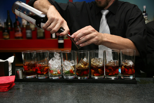 Barman pouring a rack of summer drinks.