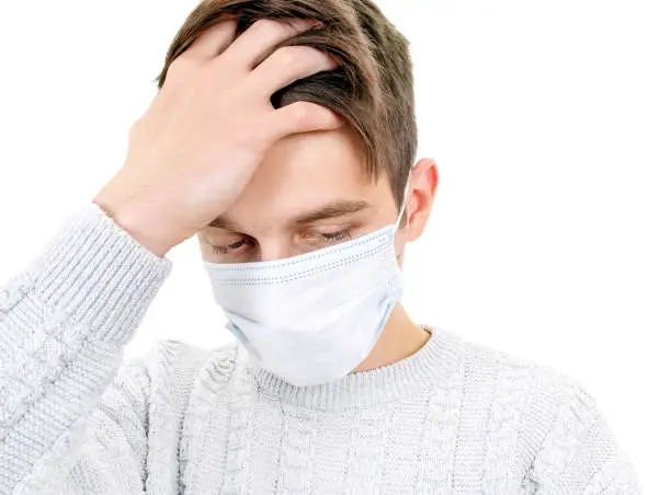 Sad and Sick Young Man in a Surgical Mask Isolated on the White Background