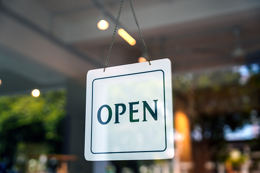 An open sign on a modern retail store hangs on the door at the entrance, symbolizing the small business concept