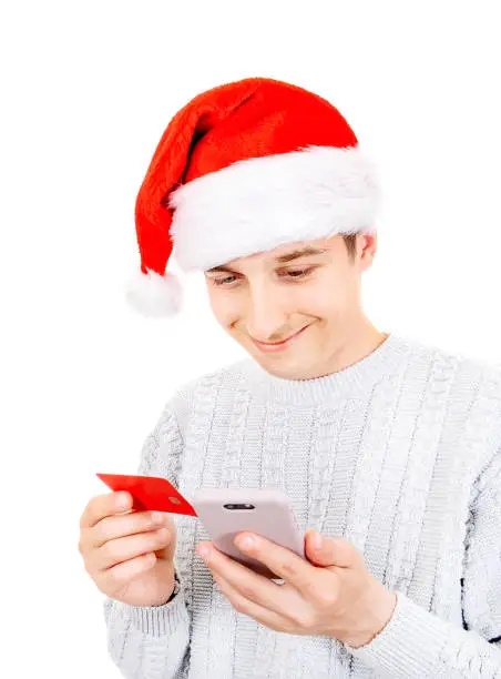 Joyful Young Man in Santa Hat with a Phone and a Bank Card on the White Background