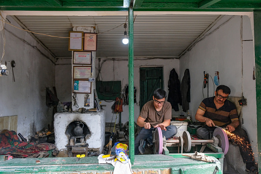 Osh, Kyrgyzstan - October 6, 2023: Men sharpening knives at the Jayma Bazaar in Osh, Kyrgyzstan.