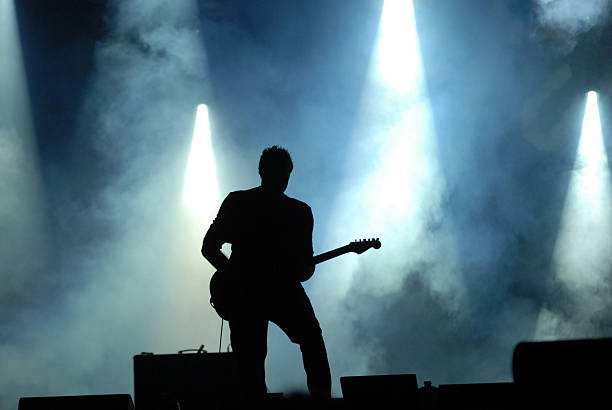 A silhouette playing a guitar at a concert stock photo