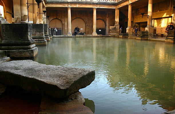 Historic Roman Bath Healing Mineral Waters in England UK Stone and columns that was built by the Romans for people to enjoy the healing powers of the water, the steamy mineral waters are England’s only naturally occurring hot springs. This Historic Roman Bath is in Bath England UK bath england photos stock pictures, royalty-free photos & images