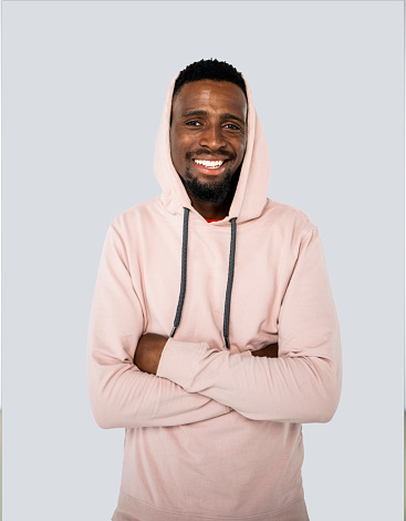 Portrait of happy young african american man wearing a hoodie standing with his arms crossed in studio
