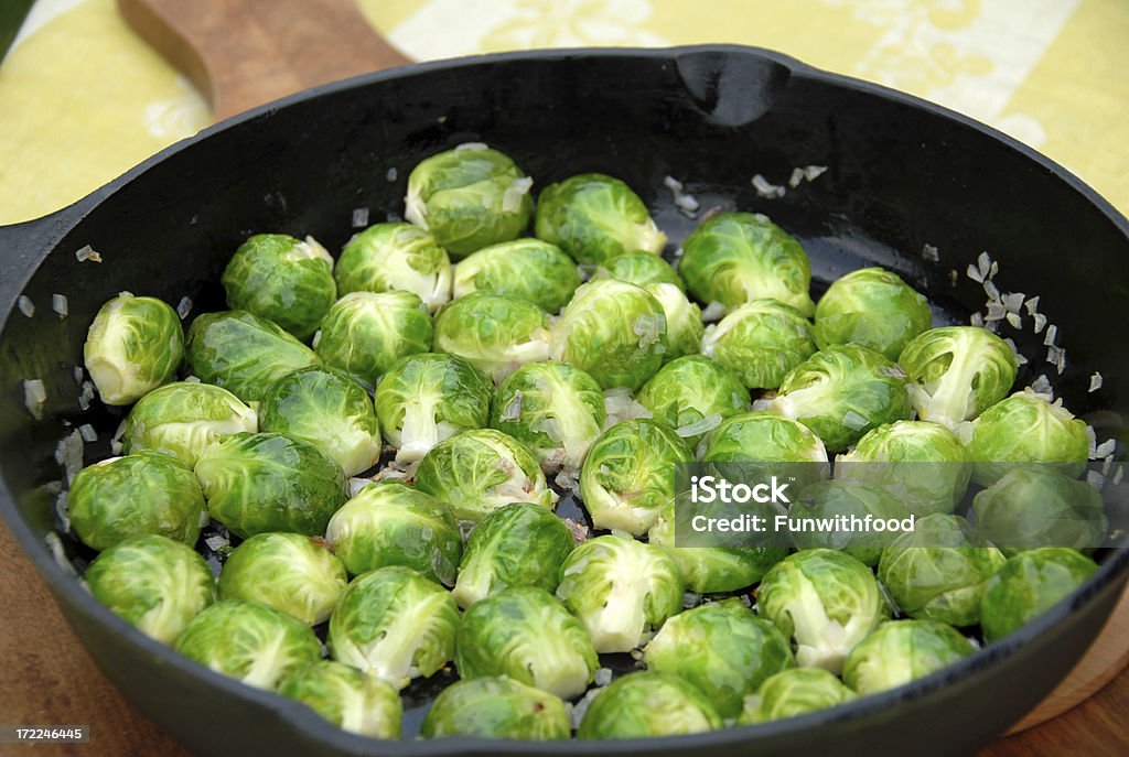 Кулинарный брюссельскую капусту: Овощи Sauteeing, приготовленных в чугун Пан - Стоковые фото Брюссельская капуста роялти-фри