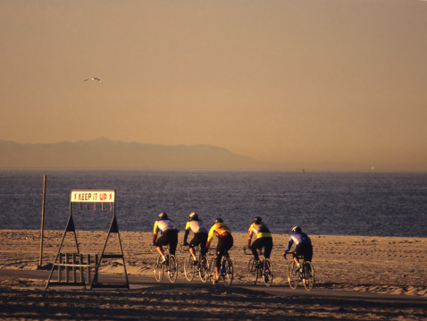 People bike riding by beach in LA.
