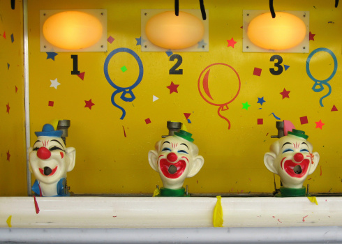 An old clown water gun balloon game at an amusement park.
