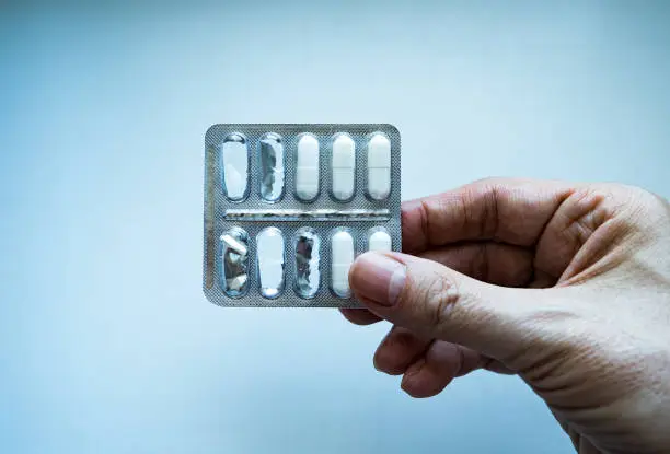 Toned Photo of Person hold a Used Pills Pack on the Wall Background closeup