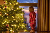 Child waiting for Santa Clause near a window in Christmas Eve
