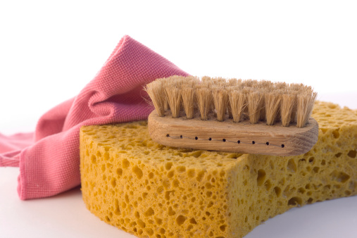 A tool kit for house cleaning and housework, including sponge, a scrub brush, and cleaning rag, againist a white background.