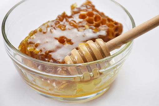Honey in a bowl with honey dipper. Fresh organic honey on white background