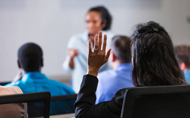 Asian woman raises hand during Q and A session