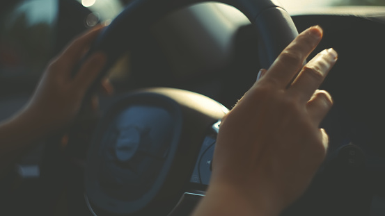 Close-up of a woman's hands gripping the steering wheel of her new car,confidently steering towards new adventures.