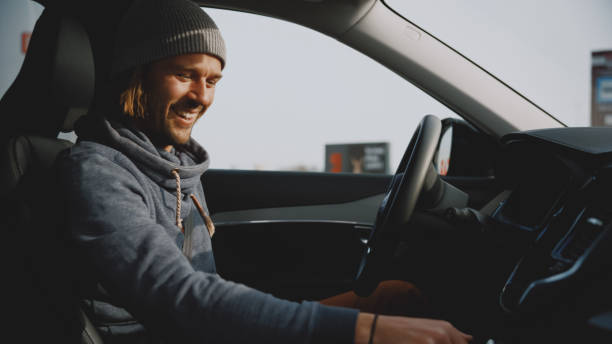 istock Cheerful young man in cap changing gear while driving modern car 1722492374
