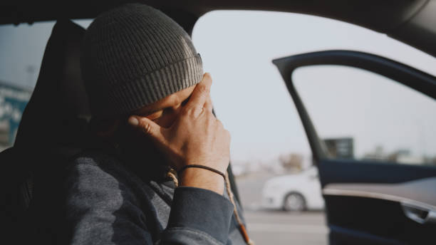 istock Depressed young man with hand on face sitting inside car with open door 1722492414