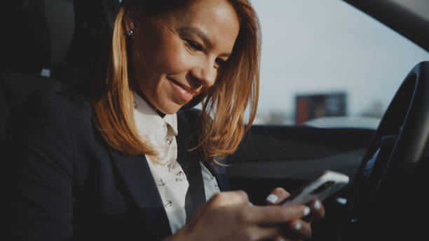 istock Smiling businesswoman using mobile phone while sitting on driver's seat in new car 1722492971