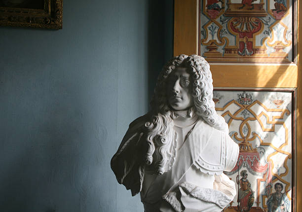 Portrait of a young creative male artist holding a gypsum statues head in front of grey background