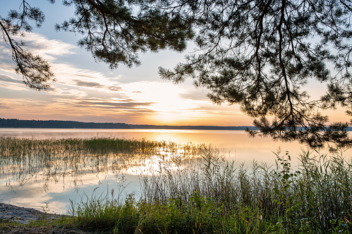 Sunrise sun looking through clouds on White Lake in Rivne region, Ukraine.