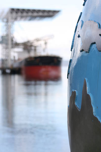 global cargo concept Australia and Singapore foreground on a steel globe illustrate distant ports for the background bulk cargo or container ship at port.  Look at more north pacific ocean globe stock pictures, royalty-free photos & images