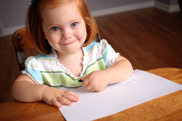 Happy Little Student in School Desk with Paper