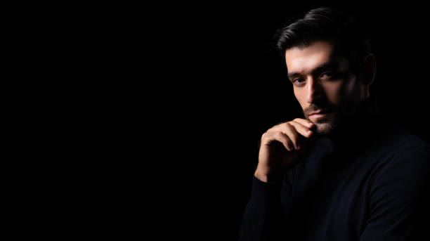 istock Pensive thinking handsome young beared man portrait Attractive bearded confident guy planning something looking at blank space Smart man thinking in the dark room Cool man get good idea imagination 1722503508