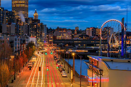 Seattle waterfront skyline with a view over the Puget Sound, and traffic light trails at sunset in Seattle, Washington, USA