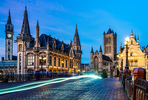 Downtown Ghent, Belgium at night with the clock tower, old post office, and St. Nicolas' church.