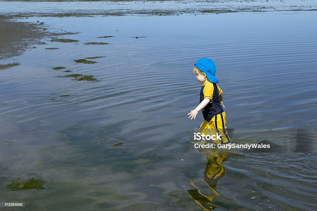 Garçon marchant dans l'eau - Photo de Casquette libre de droits