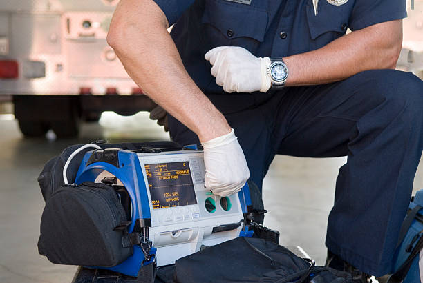 Paramedic Demonstrating a Portable Defibrillator "Fireman or paramedic demonstrating a portable defib machine, used to save lives of heart attack victims. Click below for a lightbox of all my accident and medical images:" defibrillator photos stock pictures, royalty-free photos & images