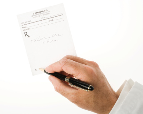 Doctor's writing a prescription with a pen.