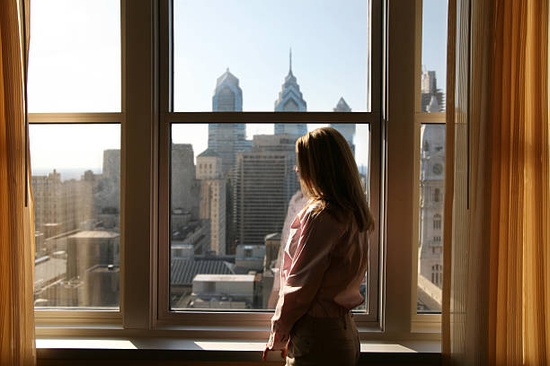 Hotel room with a view Philly'buster - Woman relaxing in her hotel room urban view stock pictures, royalty-free photos & images