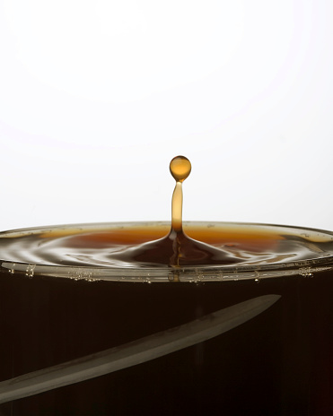 Close-up of splashing coffee - i shape in a glass. White background.