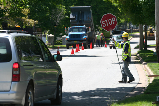 A flagman controls traffic while road repair is underway.