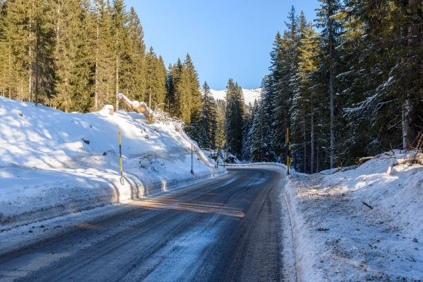 istock Mountain road through a dense snowy forest on a clear winter day 1722536692