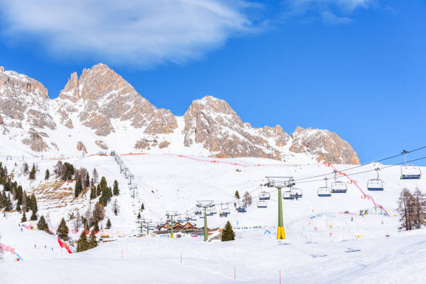 sessellifte und skipisten in einem bergort an einem sonnigen wintertag - dolomites ski lift winter ski track stock-fotos und bilder